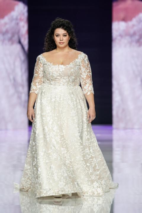 Abito da sposa curvy Sibilla in pizzo floreale con maniche a tre quarti, modello elegante su passerella.