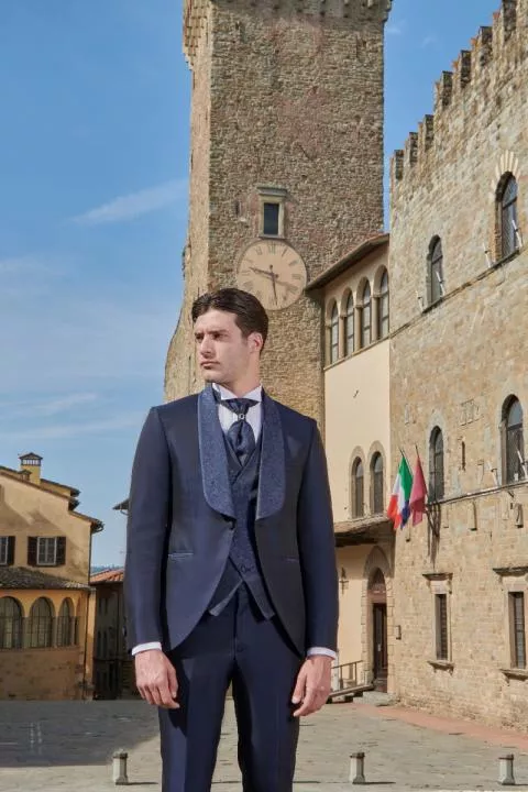 Abito elegante Rocchini 31 indossato da uomo in piazza storica con torre e orologio.