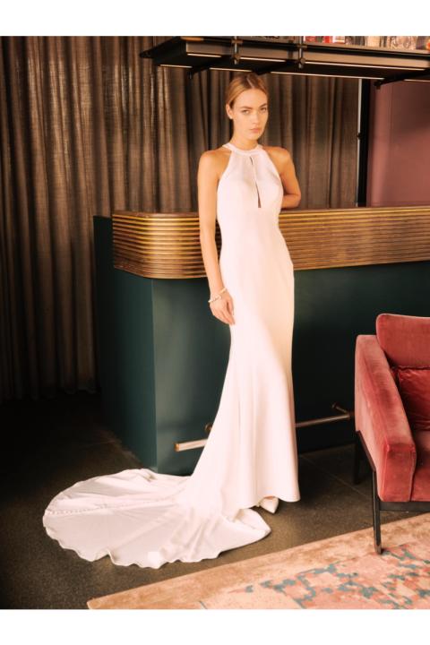Abito da sposa Algedi Sposae Essential, bianco, lungo con strascico, indossato da modella in interno elegante.