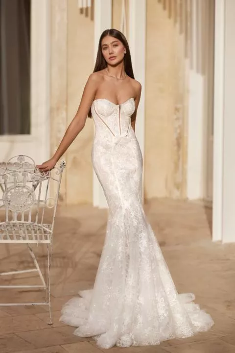 Abito da sposa AGATE di Mark Loren, design elegante in pizzo, sfondo architettonico raffinato.
