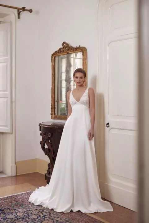 Abito da sposa elegante ANGEL di Mark Loren con scollatura a V, in ambientazione classica con specchio antico.