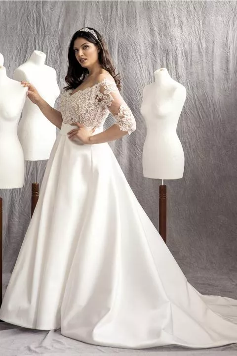 Abito da sposa curvy HAUDREY in pizzo e seta, modella tra manichini bianchi.