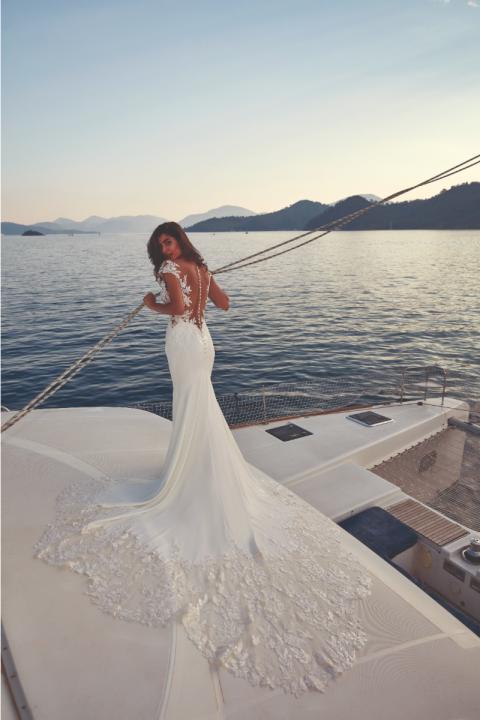 Abito da sposa DOMENICA - EDDY K con schiena scoperta e dettagli in pizzo su uno yacht al tramonto.