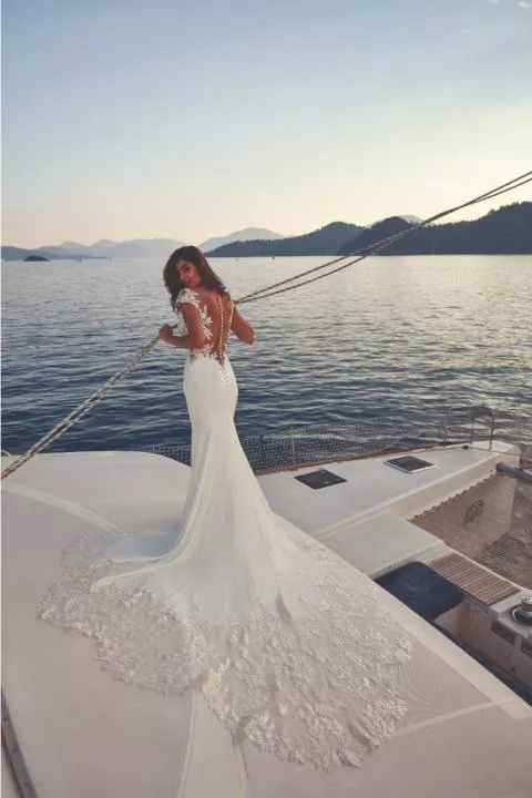 Abito da sposa DOMENICA - EDDY K con schiena scoperta e dettagli in pizzo su uno yacht al tramonto.