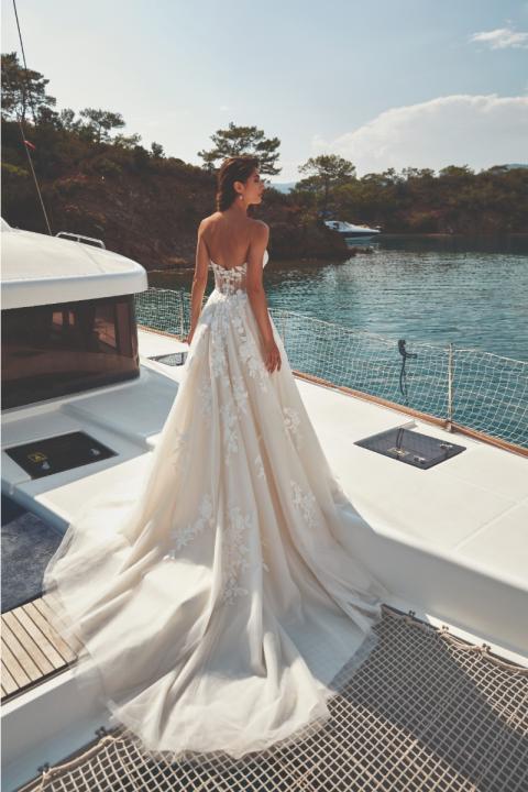 Abito da sposa Fiorella Eddy K su yacht, elegante design floreale, sfondo marino sereno.