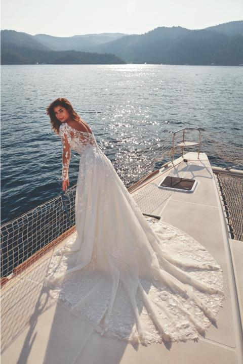 Abito da sposa UMA - EDDY K in pizzo su yacht, sfondo mare e montagne.