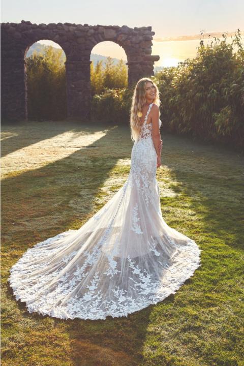 Abito da sposa Carly di Eddy K con strascico in pizzo, ambientato in un giardino al tramonto.
