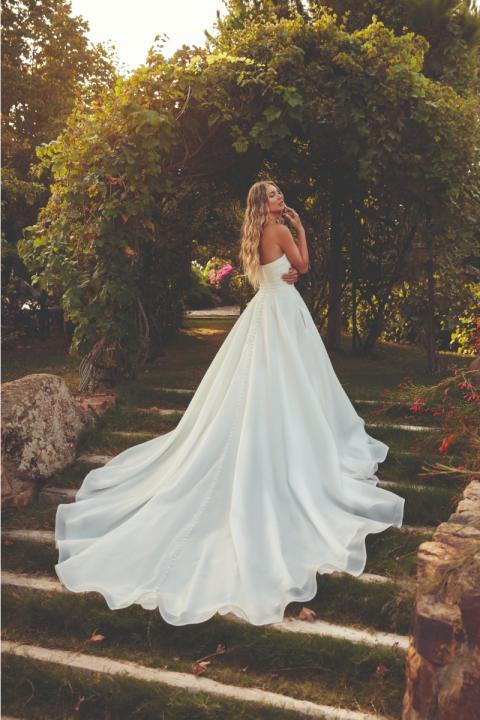 Abito da sposa TEAGAN Eddy K, scollo a cuore, lungo strascico, ambientato in un giardino romantico.
