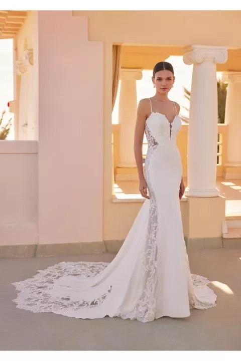 Abito da sposa ELLIOT di St. Patrick con pizzo e strascico, ambientato in una location elegante con colonne.