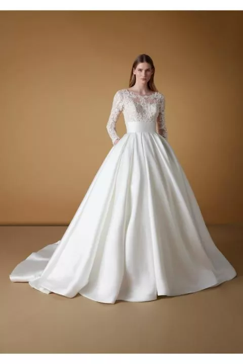 Abito da sposa ELVIRE in pizzo e seta, maniche lunghe, gonna ampia, sfondo neutro.