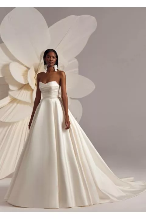 Abito da sposa bianco Dallas di Eva Lendel con scollo a cuore e gonna ampia, sfondo floreale.