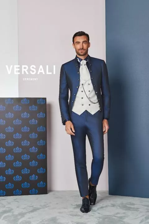 Abito da cerimonia uomo FIT 42 blu Versali, giacca elegante e gilet bianco, sfondo geometrico.