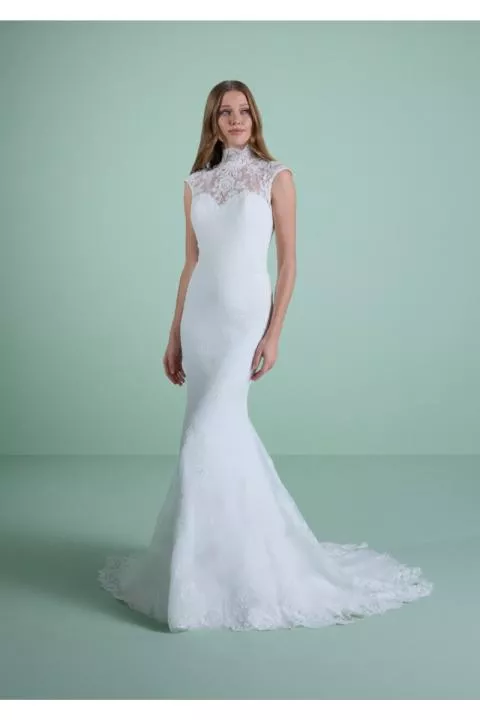 Abito da sposa HELIADE in pizzo bianco, silhouette a sirena, sfondo verde pastello.