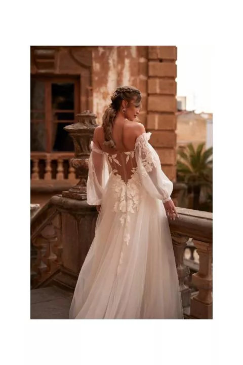Abito da sposa Hermiona Dama, schiena scoperta, dettagli floreali, maniche trasparenti, ambientazione romantica.