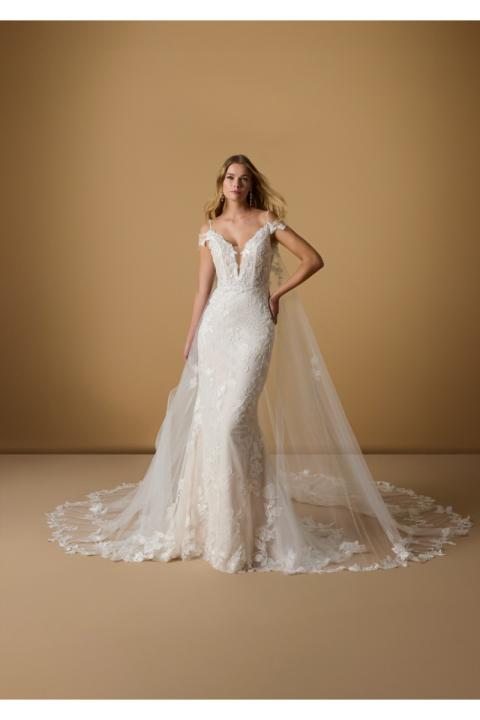 Abito da sposa INGE in pizzo con strascico, spalline sottili, sfondo beige.