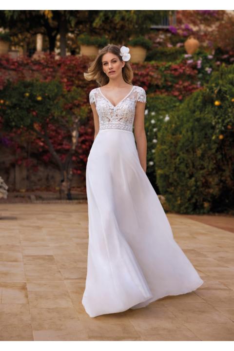 Abito da sposa bianco con corpetto in pizzo e gonna fluida, ambientato in un giardino fiorito.