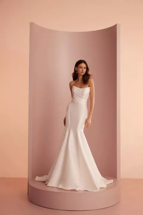 Abito da sposa bianco L403 ARIAMO LIGHT su sfondo rosa, design elegante e moderno.