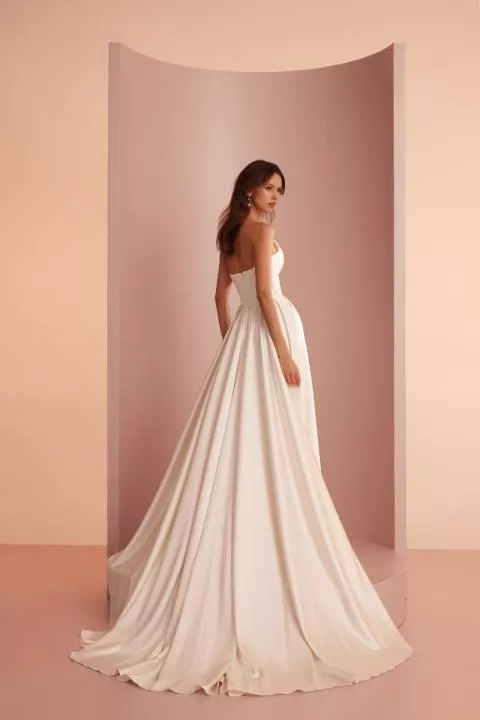 Abito da sposa ARIAMO LIGHT L415, elegante e senza spalline, con lungo strascico, sfondo rosa.