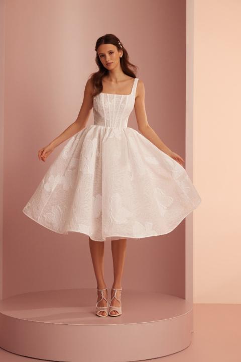 Abito bianco elegante L424 ARIAMO LIGHT con corpetto strutturato e gonna ampia, sfondo rosa.