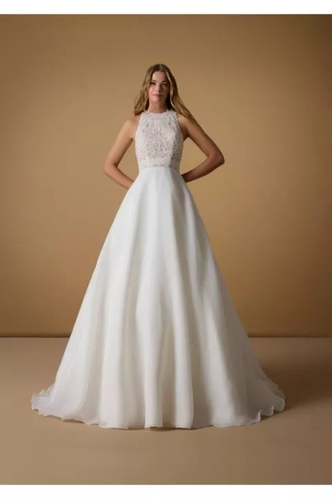 Abito da sposa MANAISHA in pizzo e chiffon bianco, senza maniche, sfondo marrone.