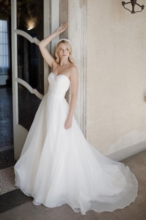 Abito da sposa Venere Linea Sposae Atelier, elegante con scollo a cuore e gonna ampia, ambientato in interni raffinati.