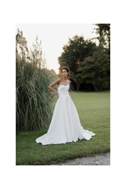 Abito da sposa elegante Capricorn di Sposae Atelier, modello senza spalline, ambientato in un giardino verde.