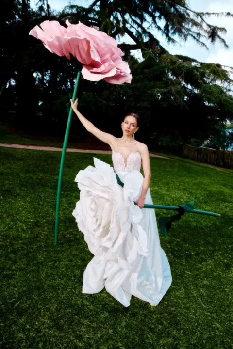 Abito da sposa NAERA con decorazioni floreali giganti, ambientato in un giardino verde.