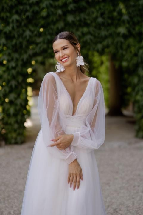 Abito da sposa ADELE - ROMANTICA BY SPOSAE, maniche trasparenti, sfondo verde naturale.