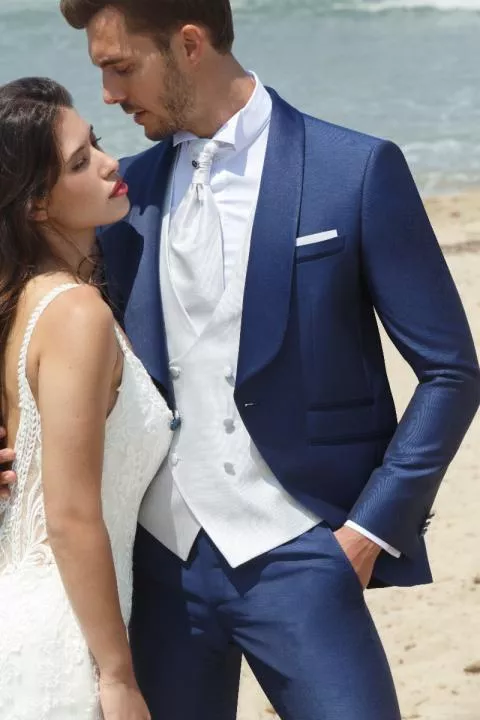 Abito elegante uomo blu PALAZZO C8 148, con giacca e gilet bianco, su spiaggia.