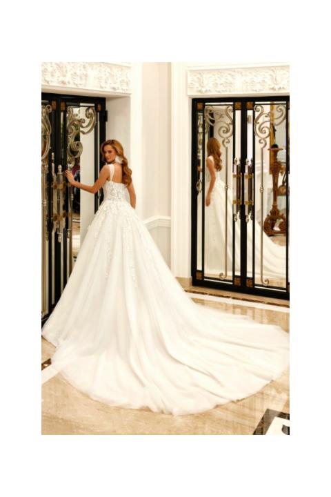 Abito da sposa ROSE di Mark Loren, elegante e lungo con dettagli floreali, indossato in un interno lussuoso.