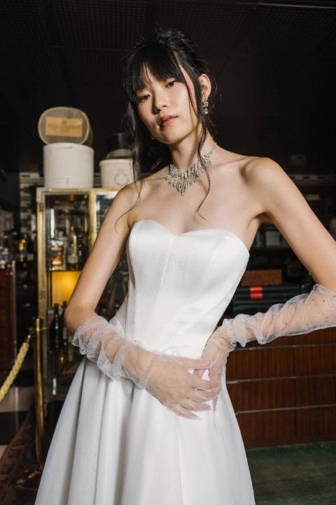 Abito da sposa bianco senza spalline, modello Cinderella di Sposae, con dettagli in tulle e gioielli eleganti.