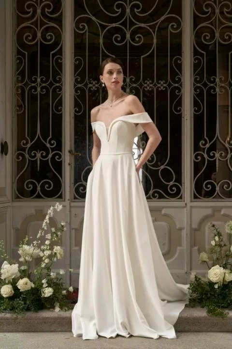 Abito da sposa elegante Flavia, collezione Romantica, con scollo a cuore e spalle scoperte, sfondo floreale.