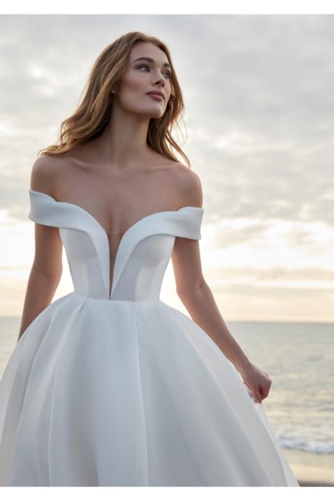 Abito da sposa TINIA scollo a cuore, sfondo mare al tramonto.