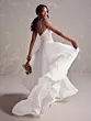 Abito da sposa Maggie Sottero Poppy, schiena scoperta e gonna fluente, donna sorridente con bouquet.