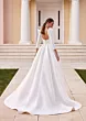 Abito da sposa Bertha con scollo profondo e maniche lunghe, sfondo scalinata e colonne bianche.
