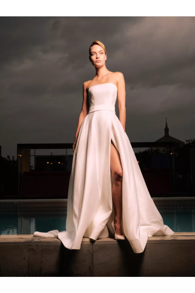 Abito da sposa Shanghai Sposae Essential, elegante e moderno, con spacco, indossato all'aperto con cielo nuvoloso.