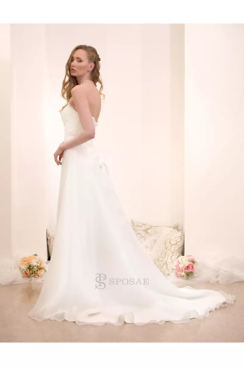 Abito da sposa elegante con strascico, modello senza spalline, ambientato in uno showroom con decorazioni floreali.