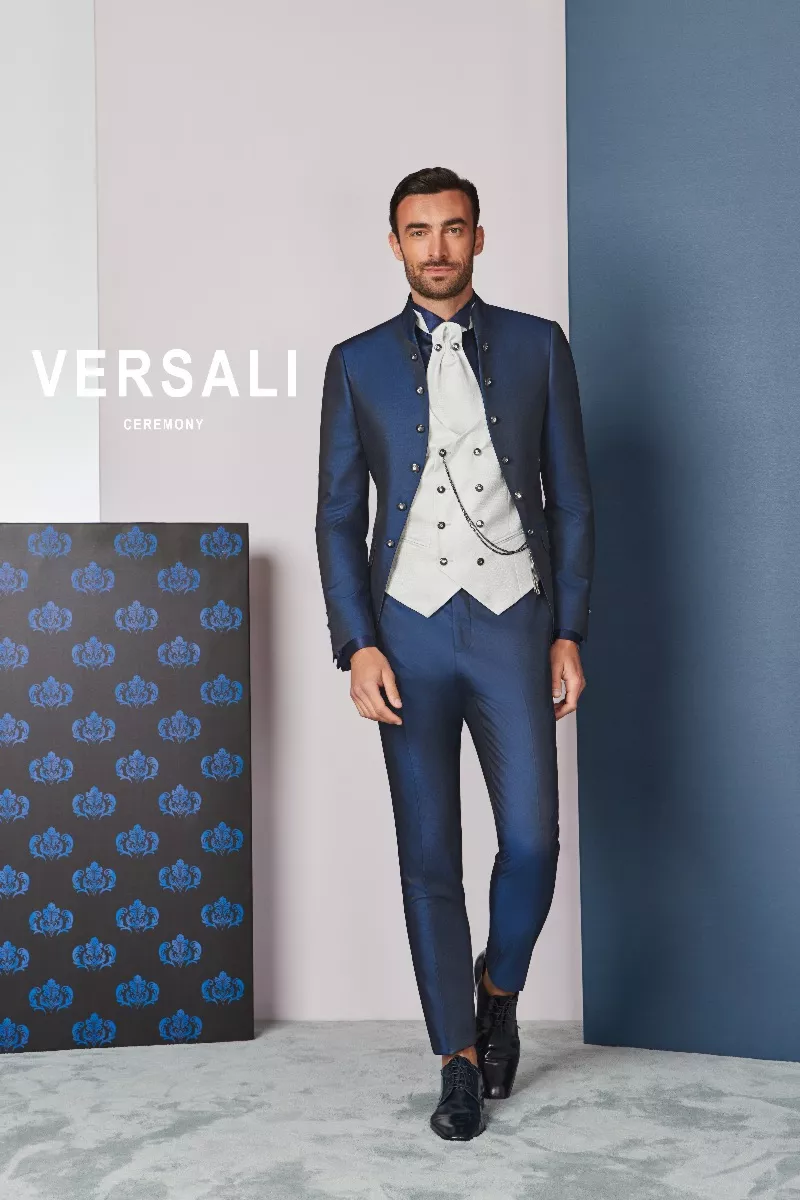 Abito da cerimonia uomo FIT 42 blu Versali, giacca elegante e gilet bianco, sfondo geometrico.