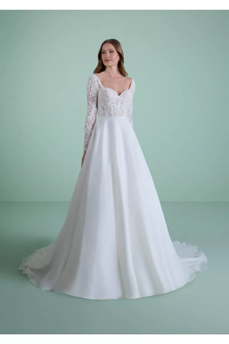 Abito da sposa HYLAS in pizzo bianco con maniche lunghe e gonna ampia su sfondo verde.