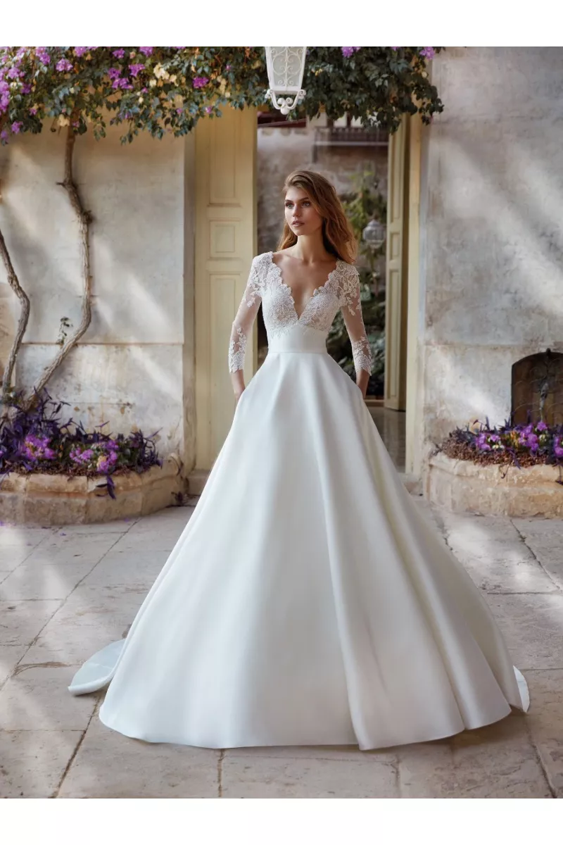 Abito da sposa KEZIA di Nicole Colet con corpetto in pizzo e gonna ampia, ambientazione romantica all'aperto.