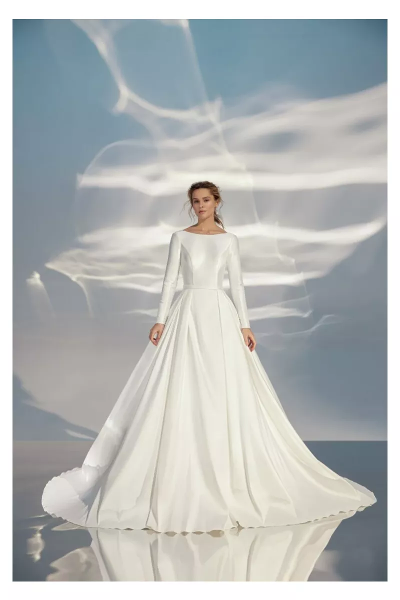 Abito da sposa L319 ARIAMO LIGHT, elegante e moderno, con maniche lunghe e gonna ampia su sfondo etereo.