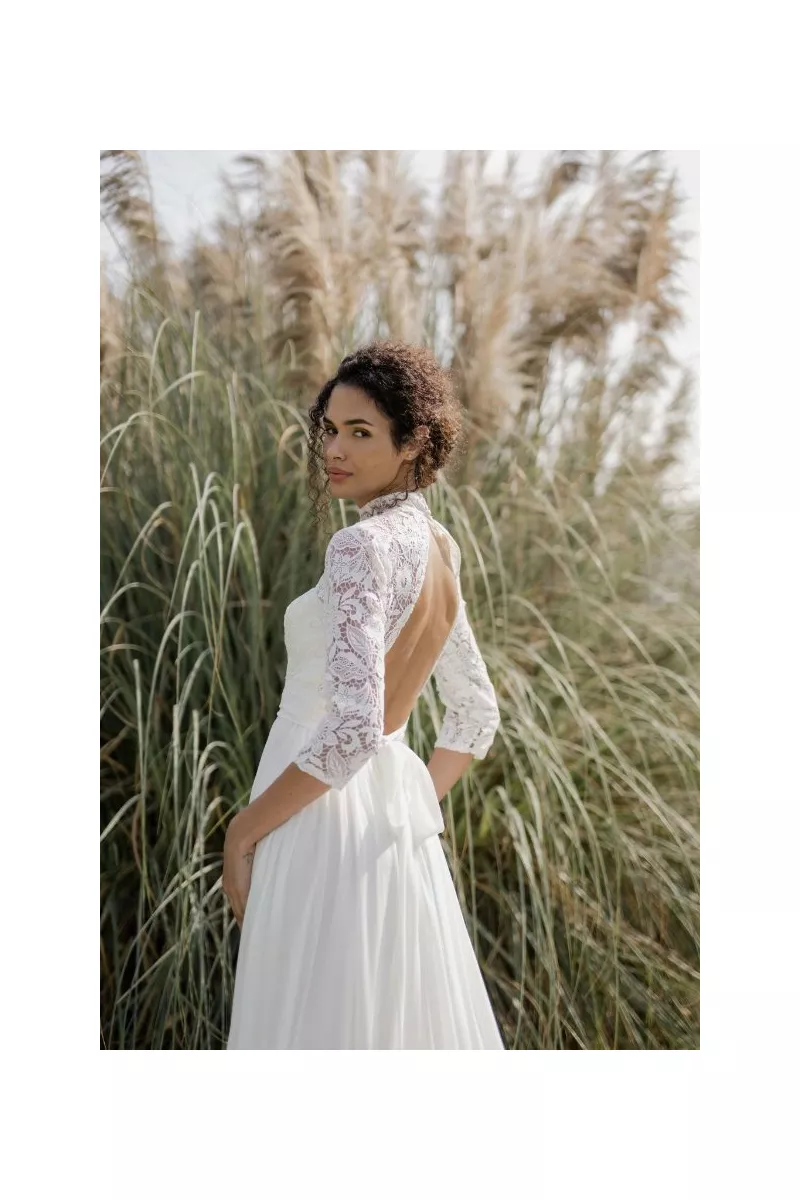 Abito da sposa in pizzo con schiena scoperta, Linea Sposae Atelier, ambientato in un paesaggio naturale.