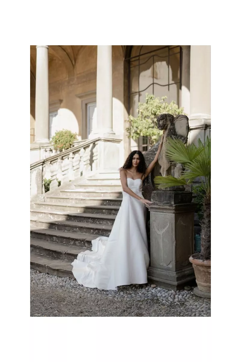 Abito da sposa Nettuno Linea Atelier Sposae, elegante design in ambientazione storica con scalinata e statua.