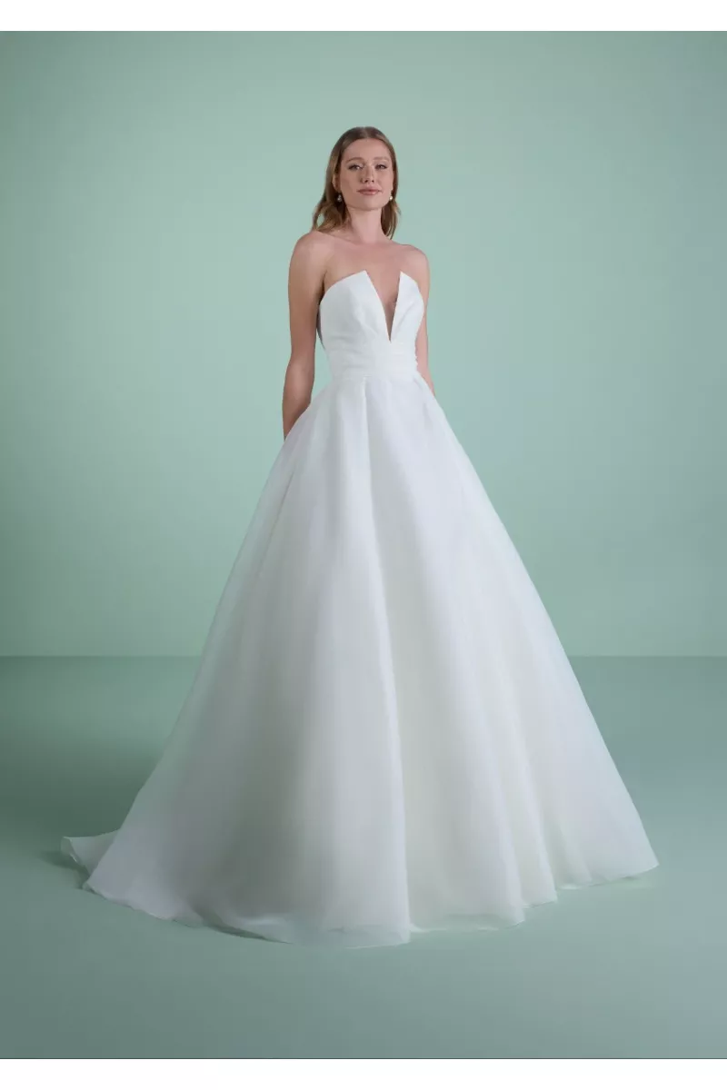 Abito da sposa THYSA bianco con scollo a cuore e gonna ampia su sfondo verde.