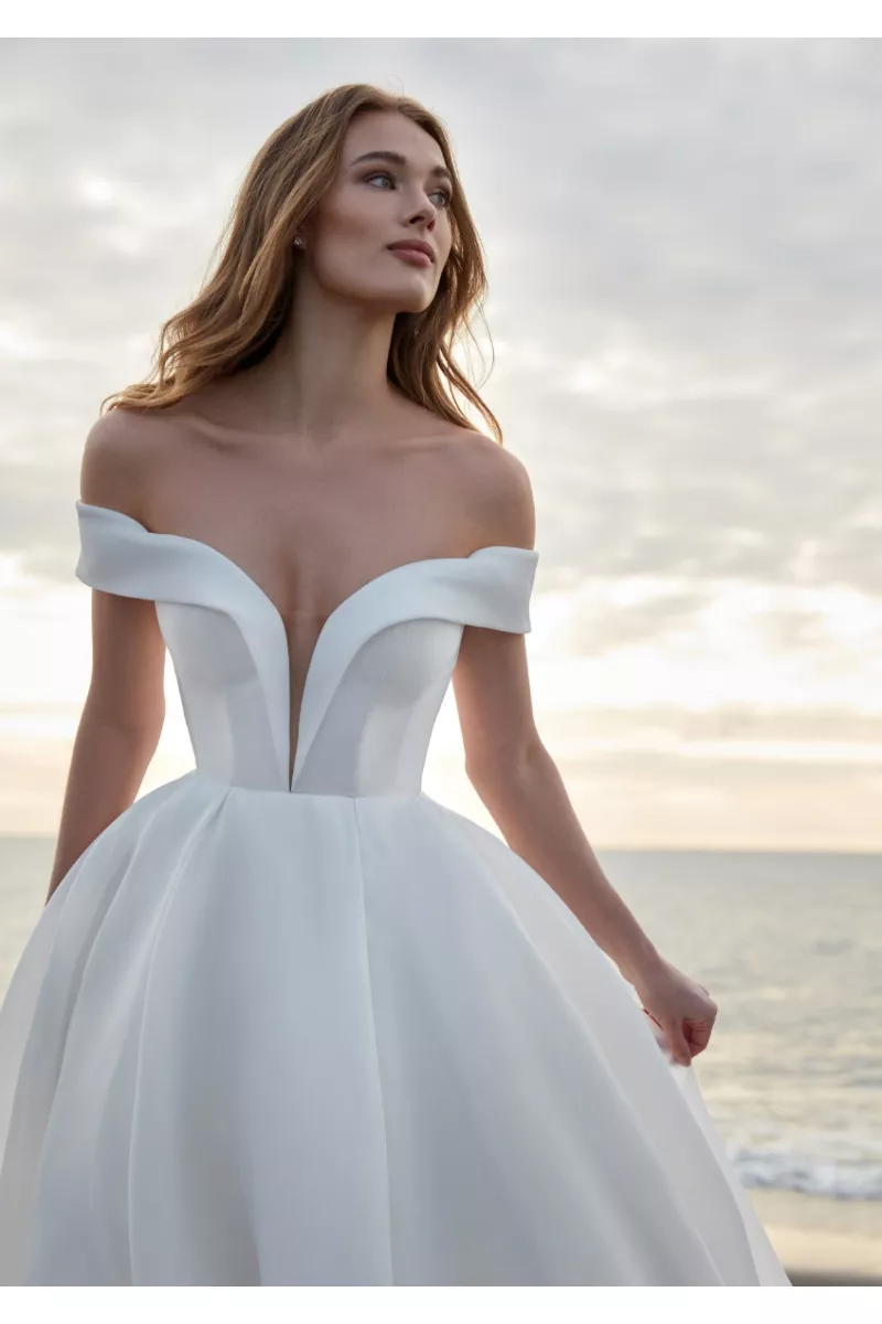 Abito da sposa TINIA scollo a cuore, sfondo mare al tramonto.