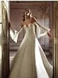 Abito da sposa MAHI elegante con maniche a campana in una stanza storica.