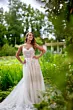 Abito da sposa Era Linea Sposae Atelier, elegante e ricamato, indossato in un giardino verde.