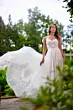 Abito da sposa Era linea sposae atelier con dettagli in pizzo, ambientato in un giardino lussureggiante.