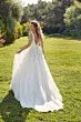 Abito da sposa Robyn Eddy K, scollo a V, dettagli in pizzo, ambientazione esterna verde.