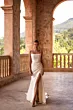 Abito da sera bianco CHARMONY DAMA con spacco, indossato in un portico storico con vista panoramica.